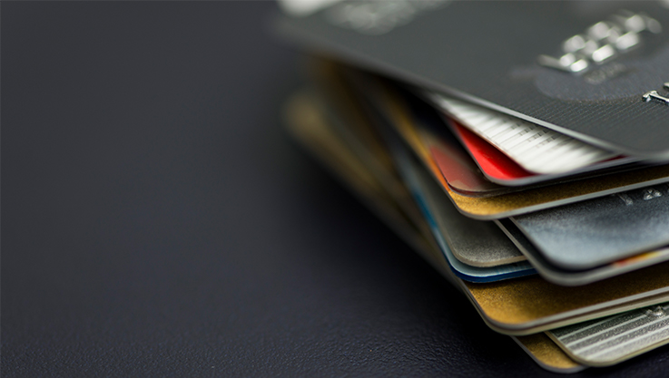 A stack of credit cards are on the right hand of the screen on a dark background.