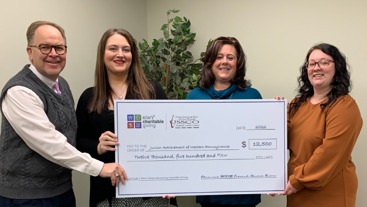 Staff members hold a large promotional check. 
