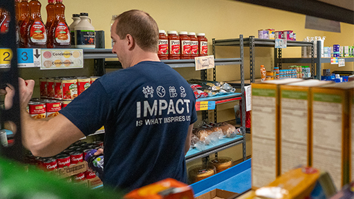 Elan volunteer stocking food shelf.