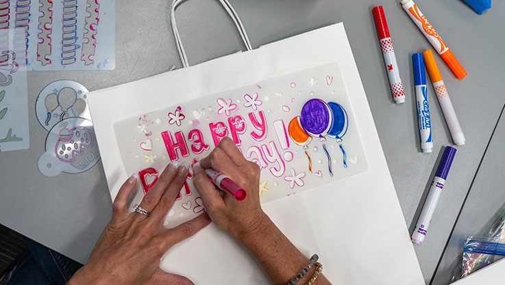 An overhead photo of a person decorating a birthday gift bag. 
