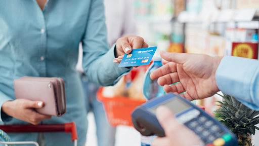 Woman in blue shirt grocery shopping and making a payment with a credit card