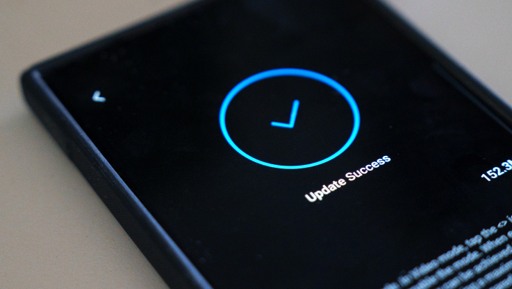 A close-up photo of a cell phone. On the screen is a blue check mark indicated updates are complete. 